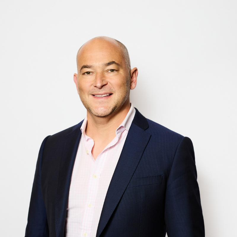 Business man with light pink shirt and black jacket smiling at camera