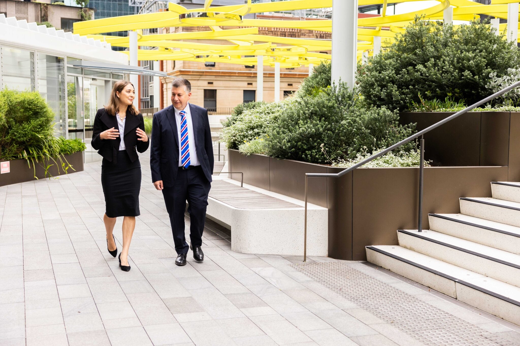 Two colleagues strolling whilst discussing some work matters
