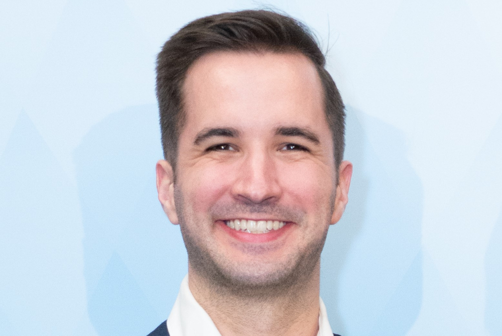 Young business man, smiling at camera with short bown hair. Head shoulders photo.