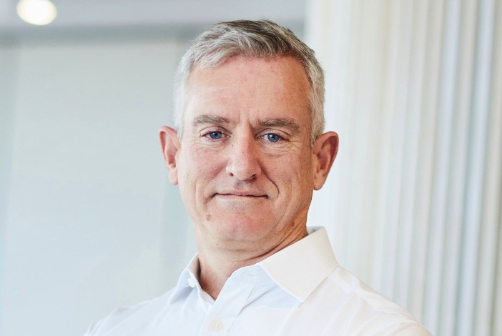 Man with white shirt and light coloured hair looking at camera