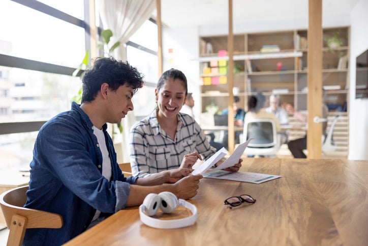 Happy team of Latin American business people working together at the office and looking at a document