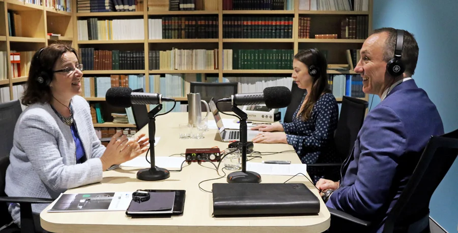 Elayne Grace and Brett Clark, CEO of TAL, recording a podcast in the Actuaries Institute library, with a producer seated between them.