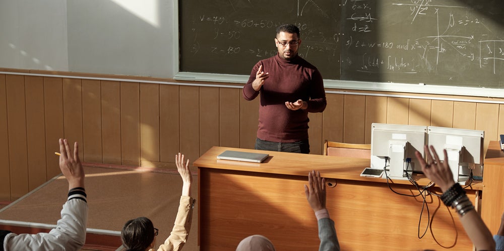 Male lecturer out front of class teaching university students