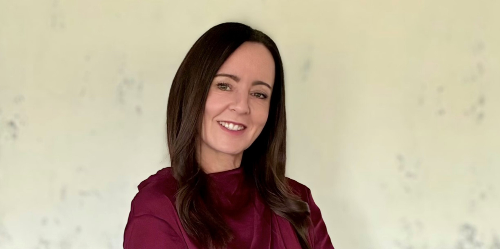 Business woman smiling at camera with arms crossed and wearing a burgundy shirt