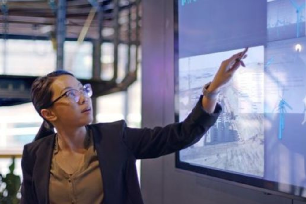 Business woman with black hair in pony tail pointing at screen and talking