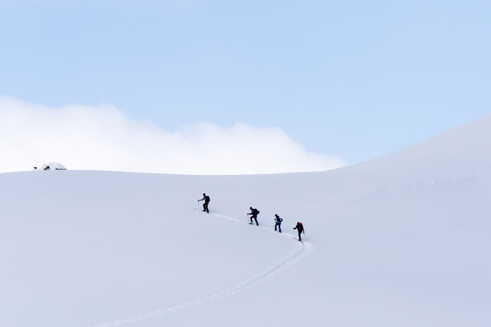 Four people walking to the top of a snow mountain