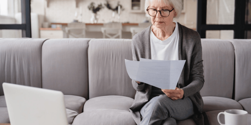 Elderly woman reading documents on a couch