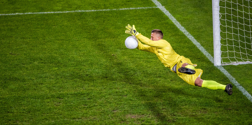 Football goalkeeper diving for a ball.