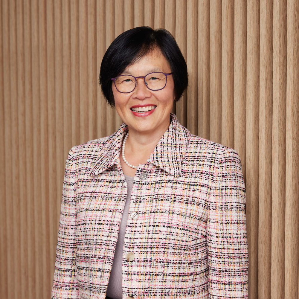 Professional portrait of Win-Li Toh. Win-Li has short black hair and round purple glasses, and smiles warmly at the camera.