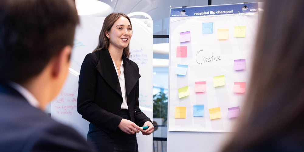 Actuary standing in front of butchers paper with post it notes brainstorming