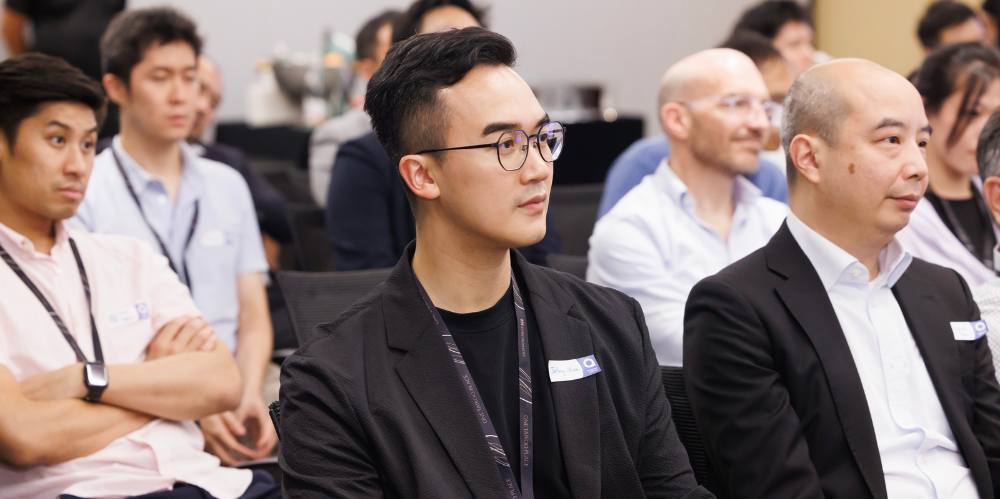 An audience of professionals sit looking away from the camera.
