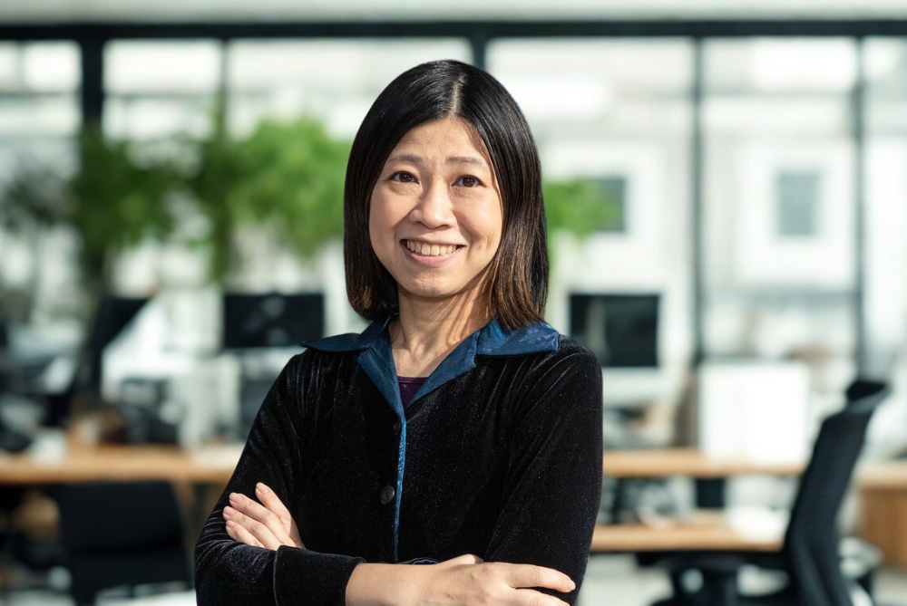 Female standing in office smiling with arms crossed.