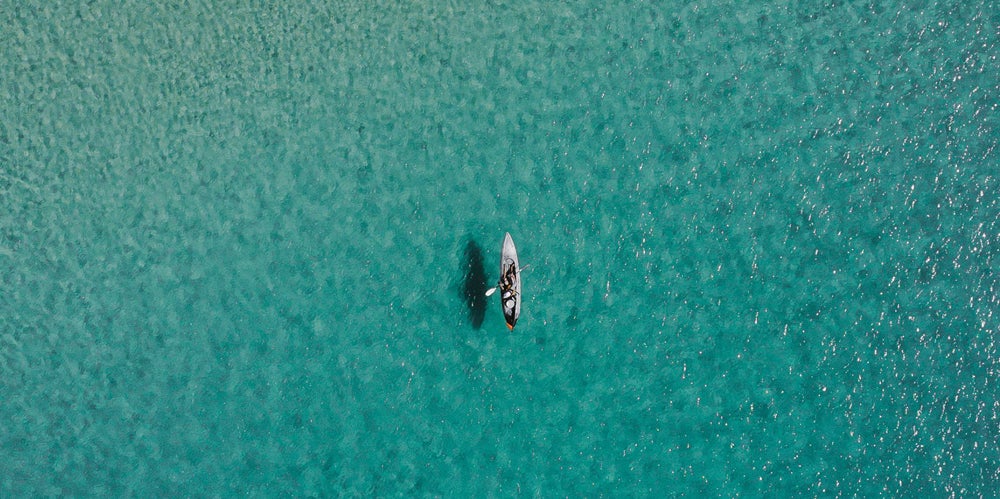 Lone paddle boarder in a beautiful blue green ocean