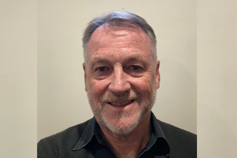 Male with beard smiling at camera in black shirt - portrait photo