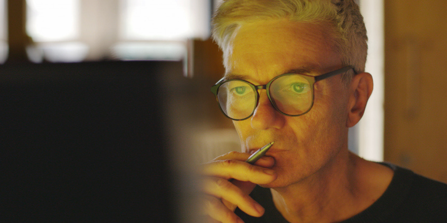 Close up image of a mature man concentrating on a computer screen.