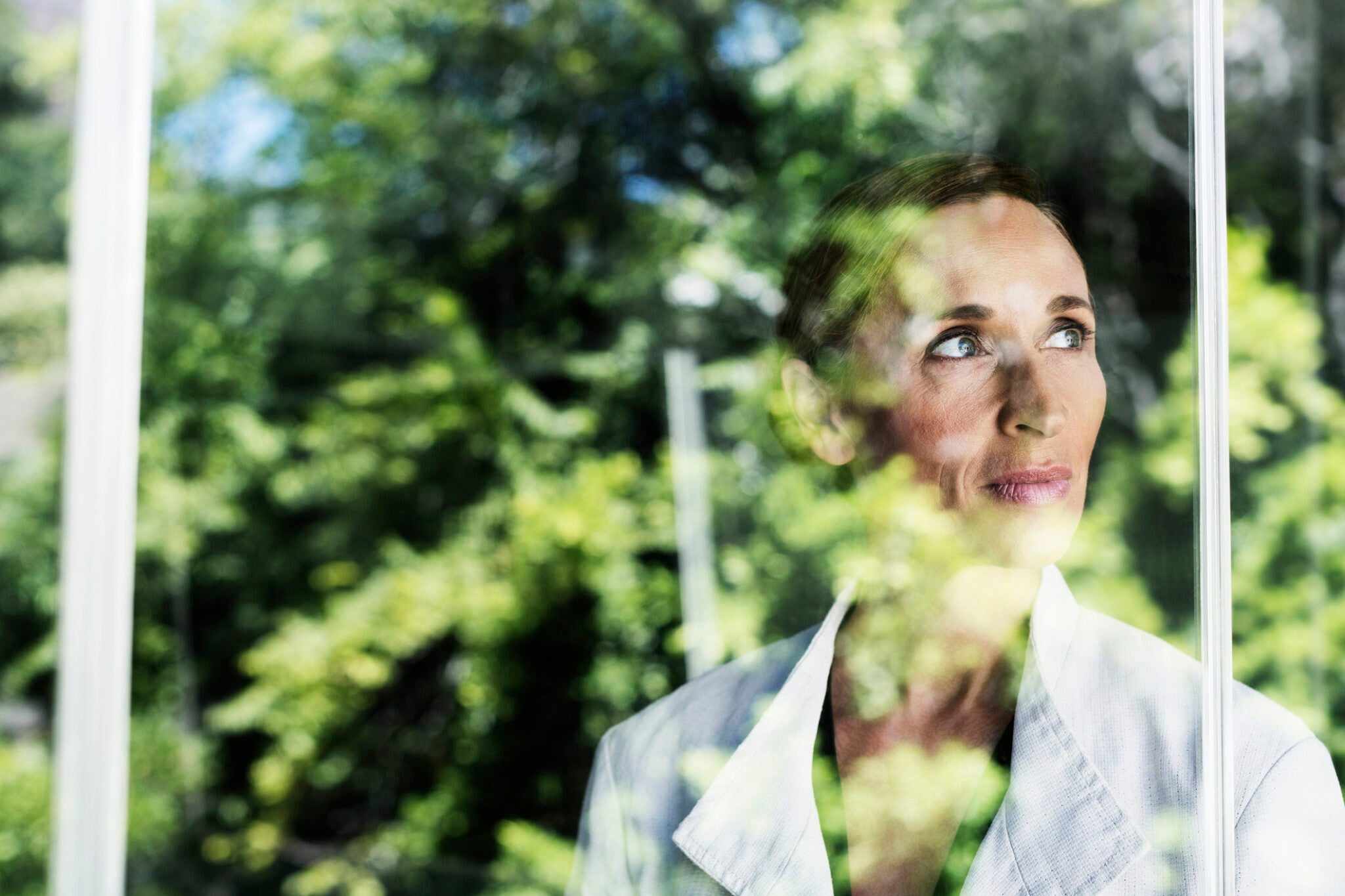Thoughtful businesswoman standing by glass window in office
