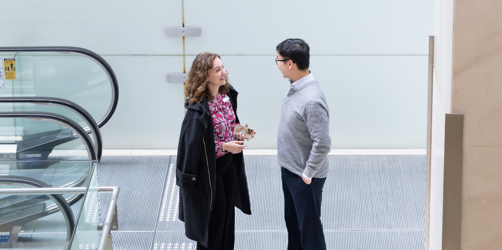 female and male at to of an escalator chatting