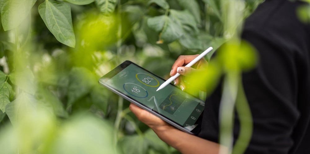 Person holding ipad and tracking data on a farm