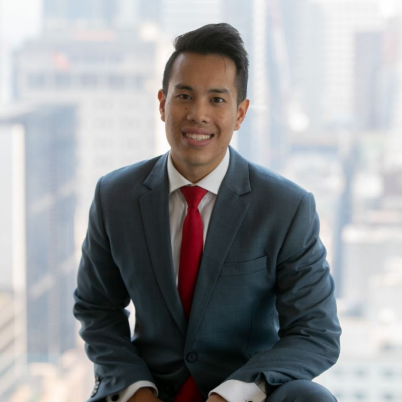 Male smiling and looking at camera in black suit and red tie