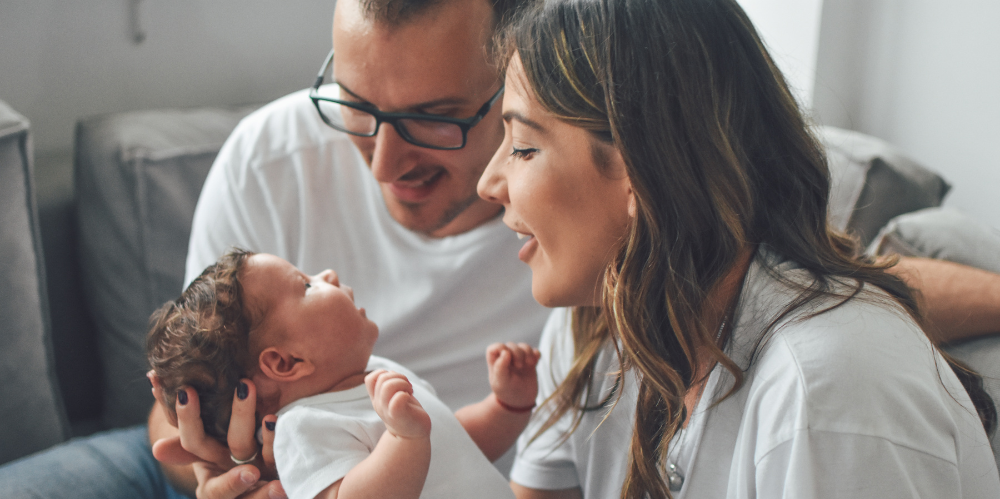 Mum and dad holding a new born baby dressed in white