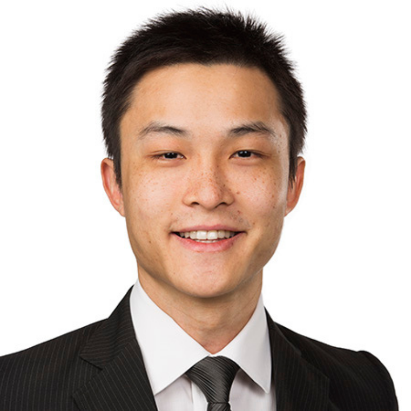 Business man with dark hair smiling at the camera, with white shirt, and black tie and jacket