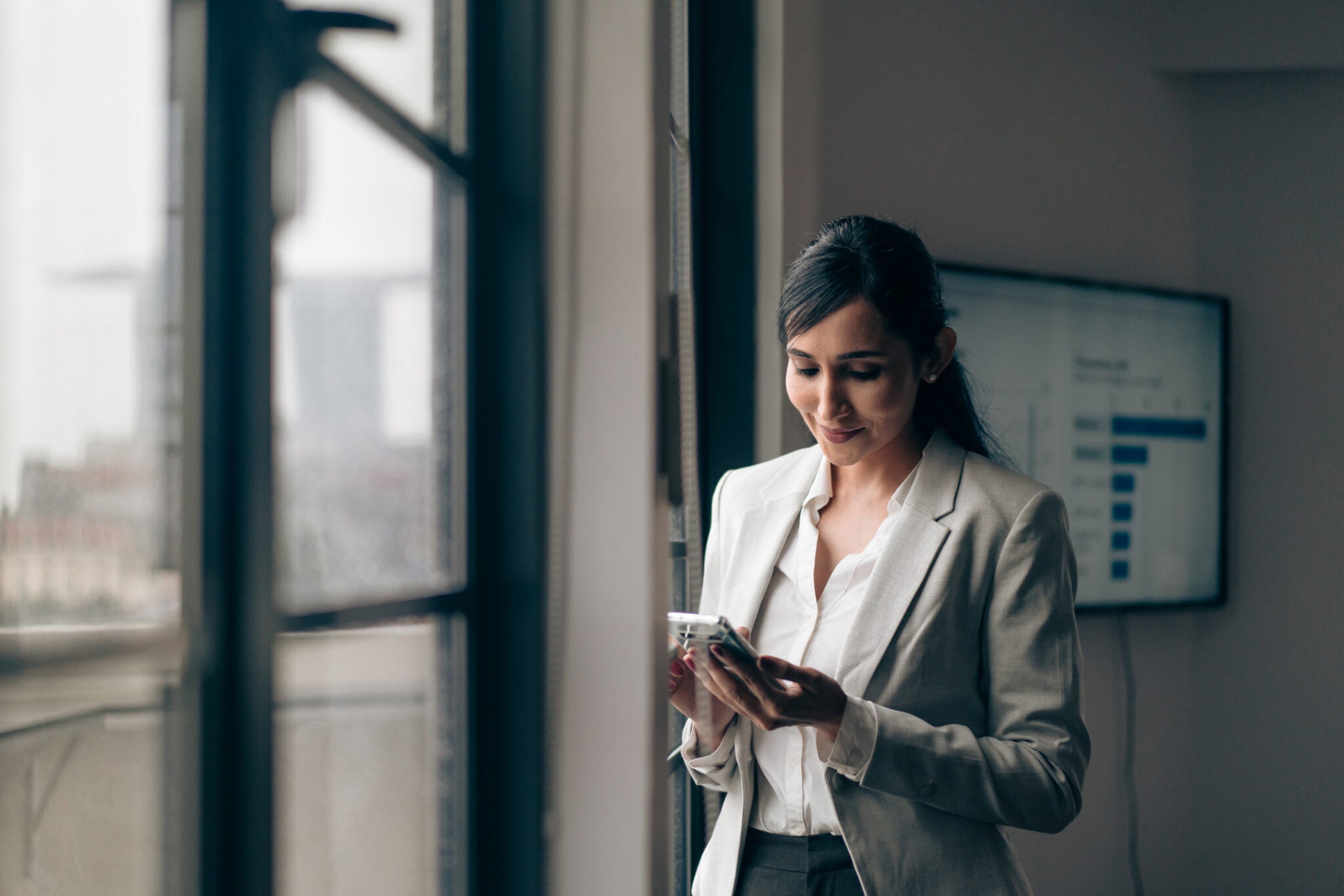 Beautiful Indian businesswoman using her mobile phone in the office