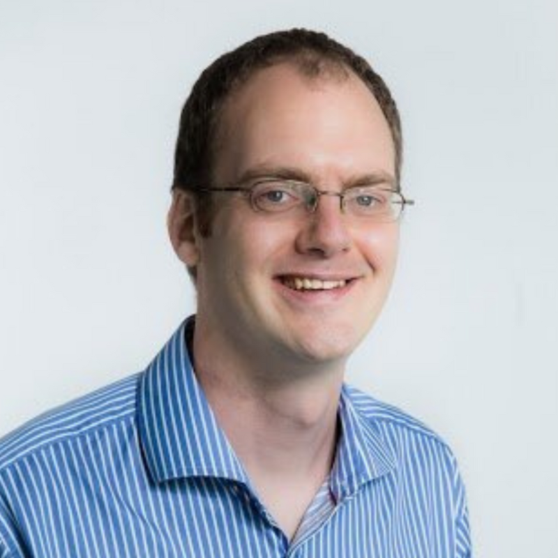 Portrait photo of Chris Dolman in blue striped shirt and glasses