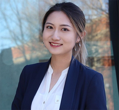 Woman in business attire stands smiling at the camera