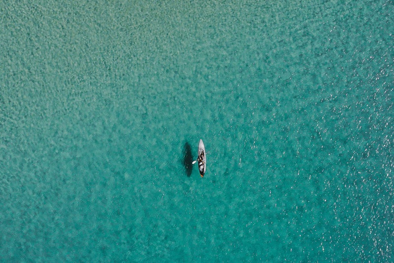 Paddle boarder in middle of beautiful blue ocean