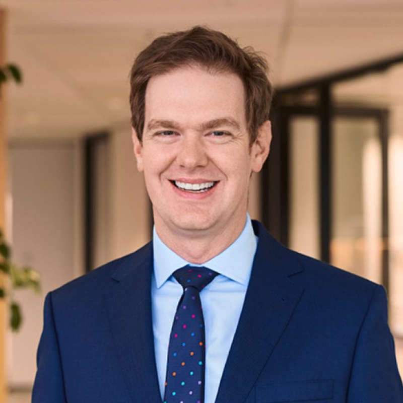 Portrait photo of Hugh Miller in navy blue suit and tie, and light blue business shirt
