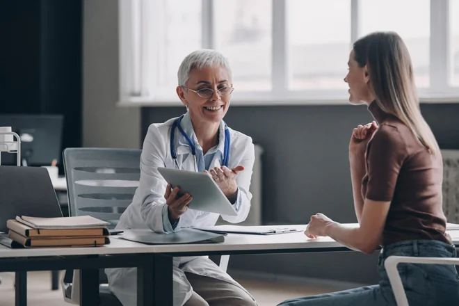 Confident female doctor pointing digital tablet while consulting patient in the medical office.