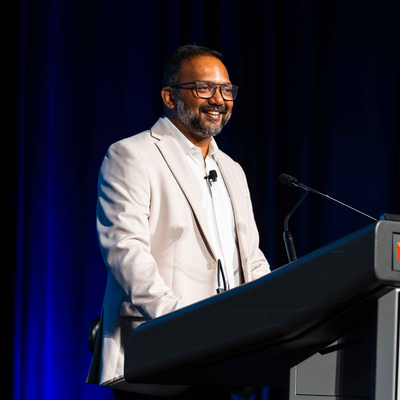 Suhit Anantula gesturing while speaking on the panel, with Jacki Johnson seated beside him
