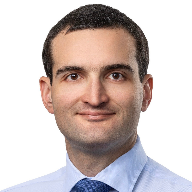 Business man with brown hair, blue shirt and dark blue tie looking at camera