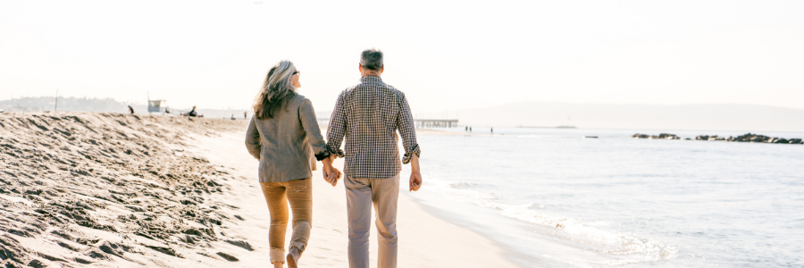 retired couple walking along a beach