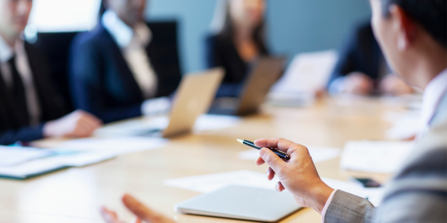 Hands of businessman gesturing ideas decisions with pen pointing leadership to work colleagues in business meeting at board room conference table