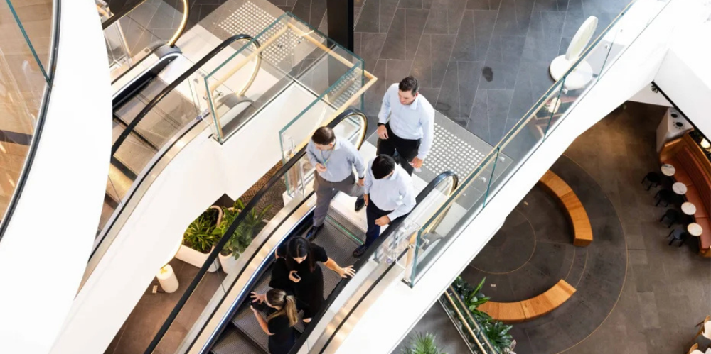 Professionals walking through the atrium of a modern commercial office building.