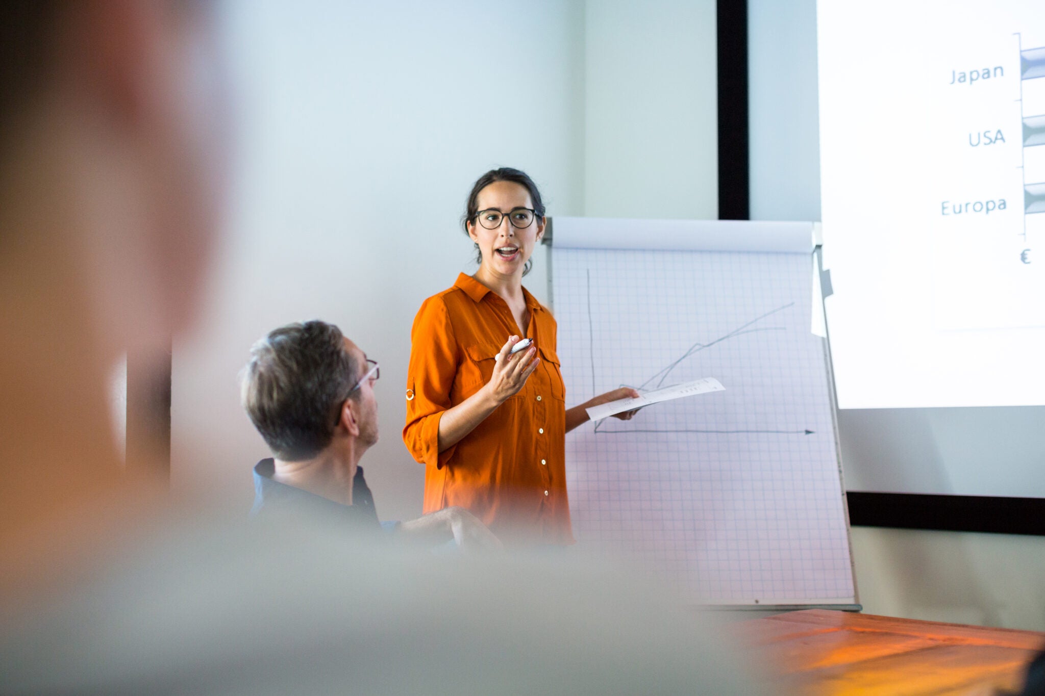 Businesswoman giving presentation to colleagues in conference room. Female entrepreneur explaining new business strategy to colleagues at boardroom.