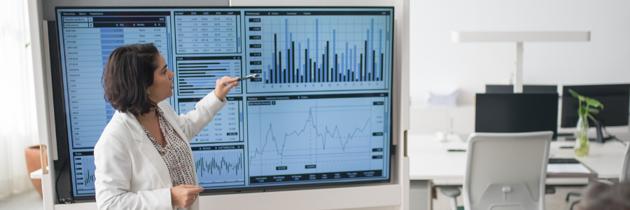 Woman standing and looking at data on screen.