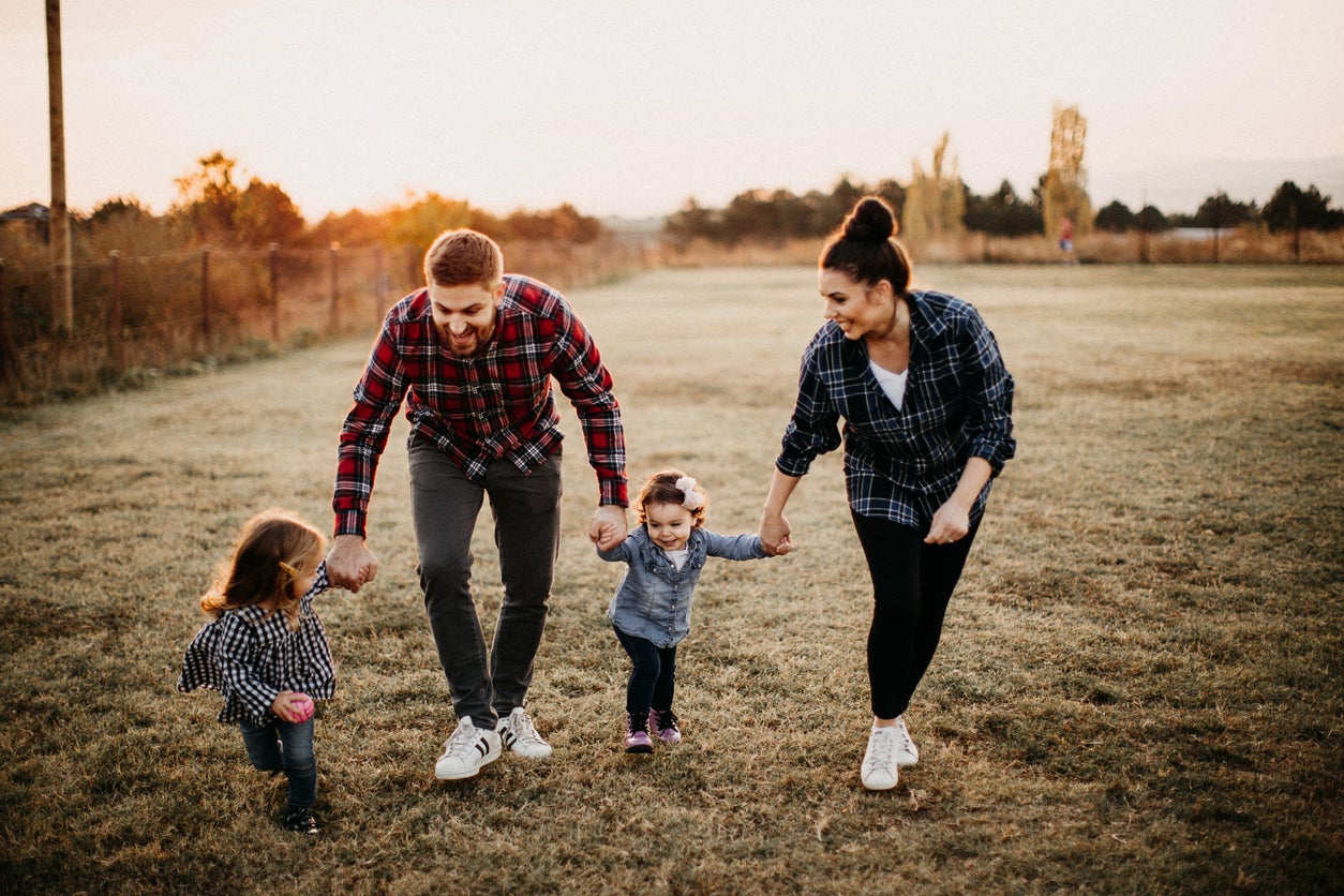 Parents carrying kids, playing on meadow