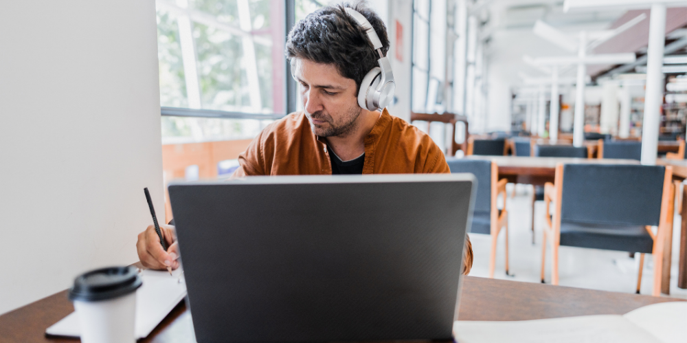 Mid adult man working using laptop at library.