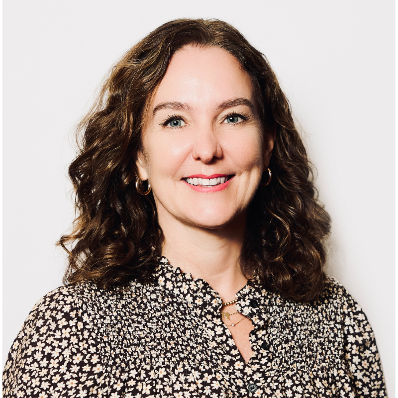 Women smiling looking at camera with brown hair and black and white blouse