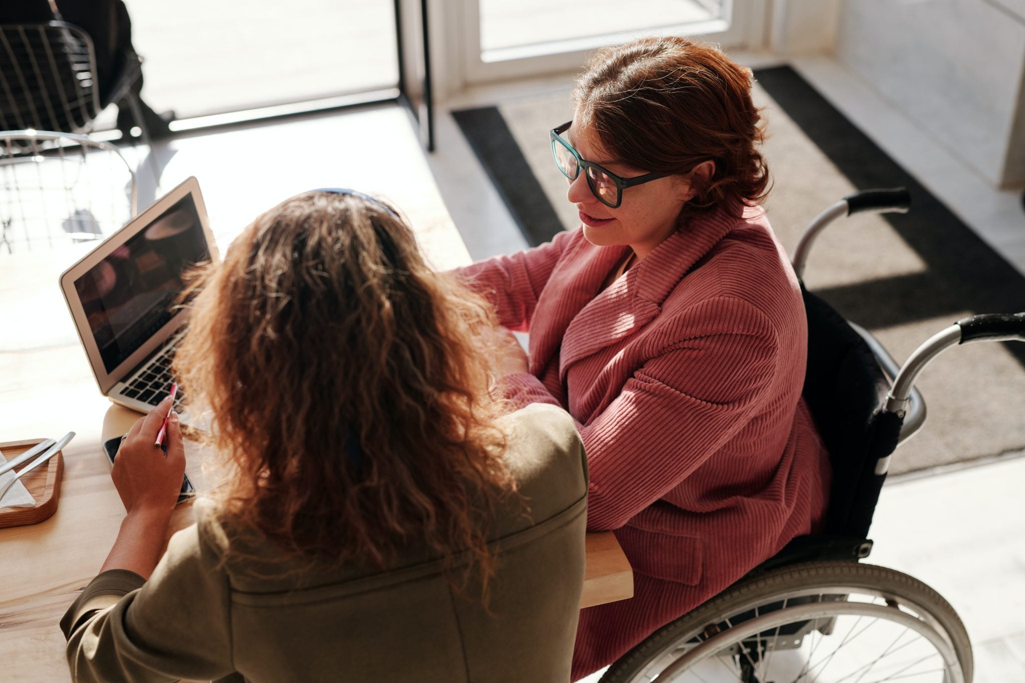 A women in a wheel chair talking to a friend at a cafe.