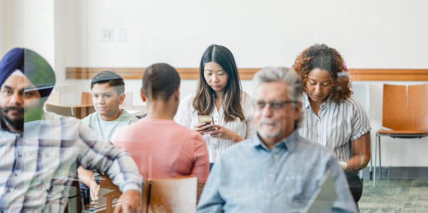 A multiracial, multigenerational group of people sit in the clinic waiting room