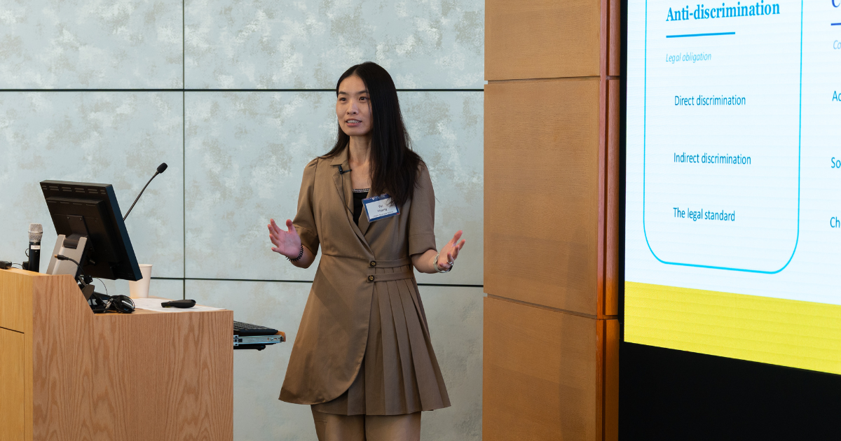 Woman standing at lectern presenting.
