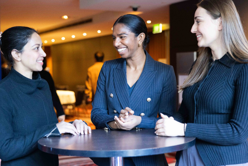Three women in navy suits chatting to each other and smiling