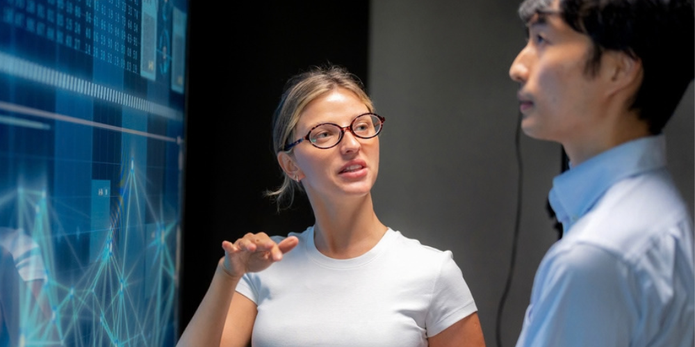 Female programmer explaining infographic on screen.