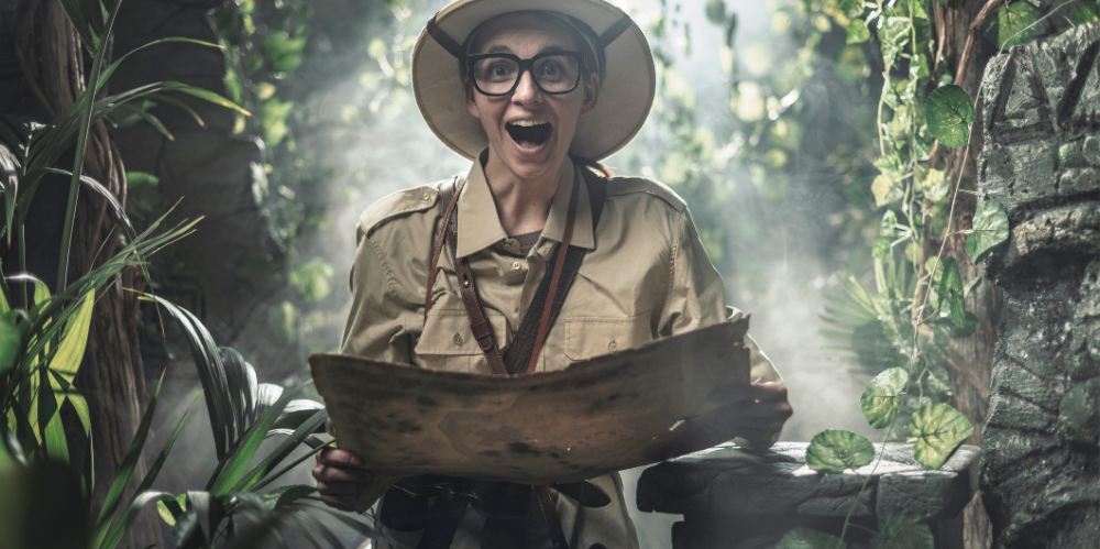 Cheerful woman exploring a tropical jungle with a map, she finds some ancient ruins.