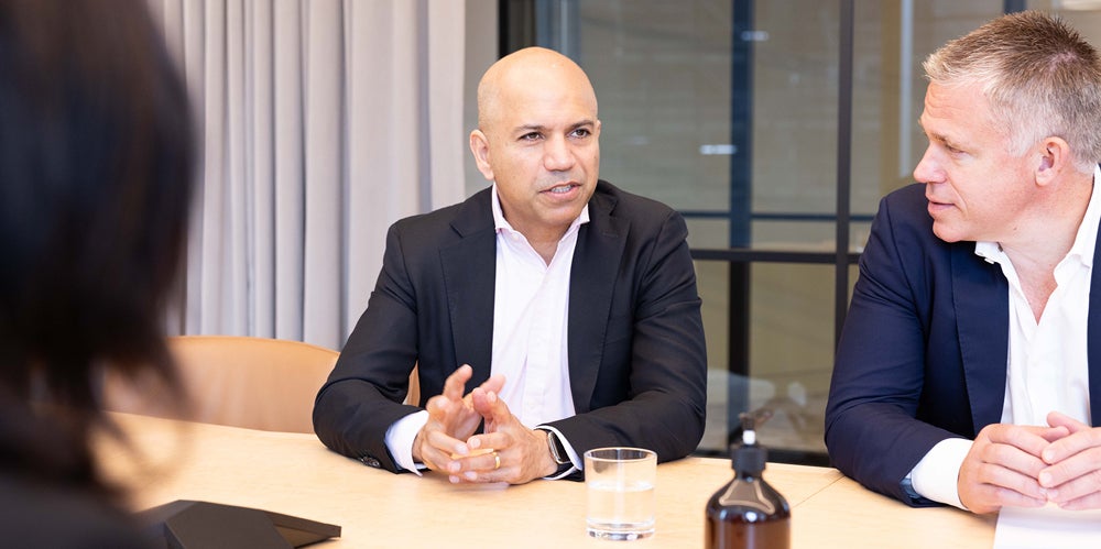 Three actuaries sitting at a board table discussing important issue