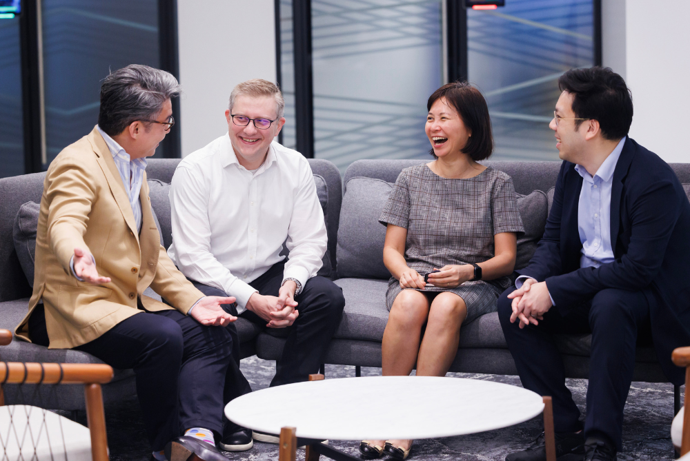 Four business people sitting casually on a large lounge chatting and laughing