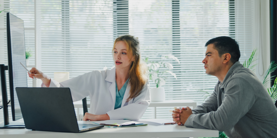 Young female doctor explaining X-ray results to adult male patient during consultation in the clinic office